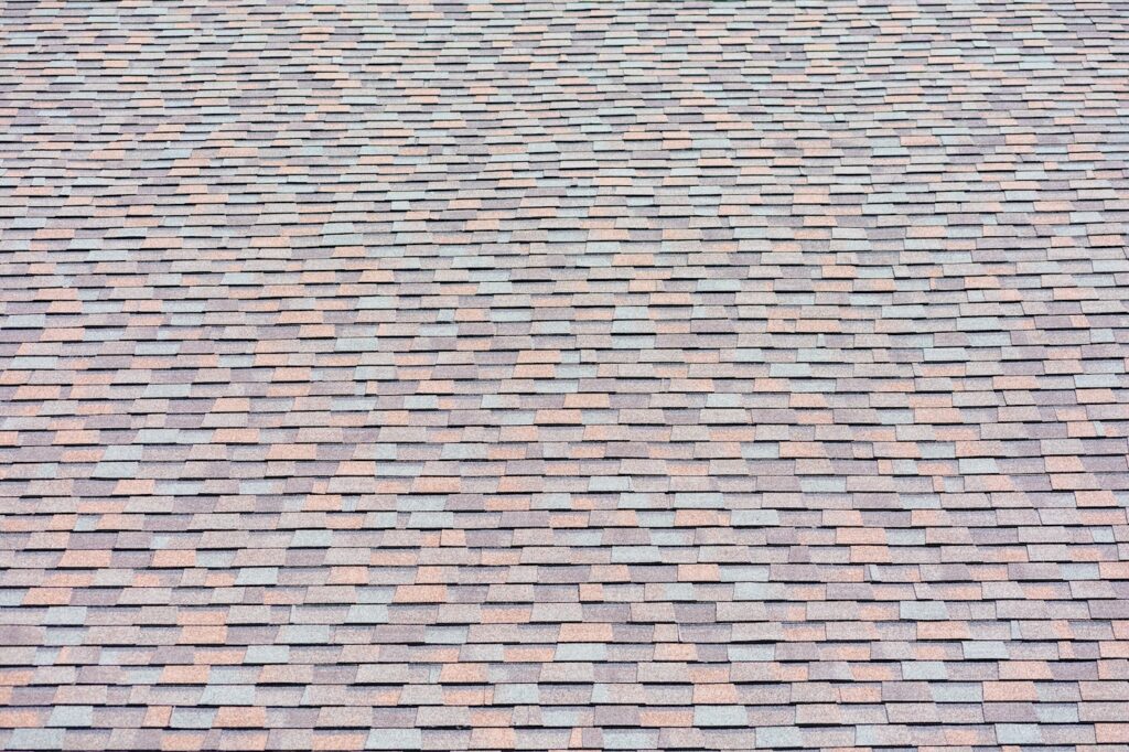 Laminated architectural roof shingles with ridge shingle of different shapes and sizes give the rooftop dimensional appearance