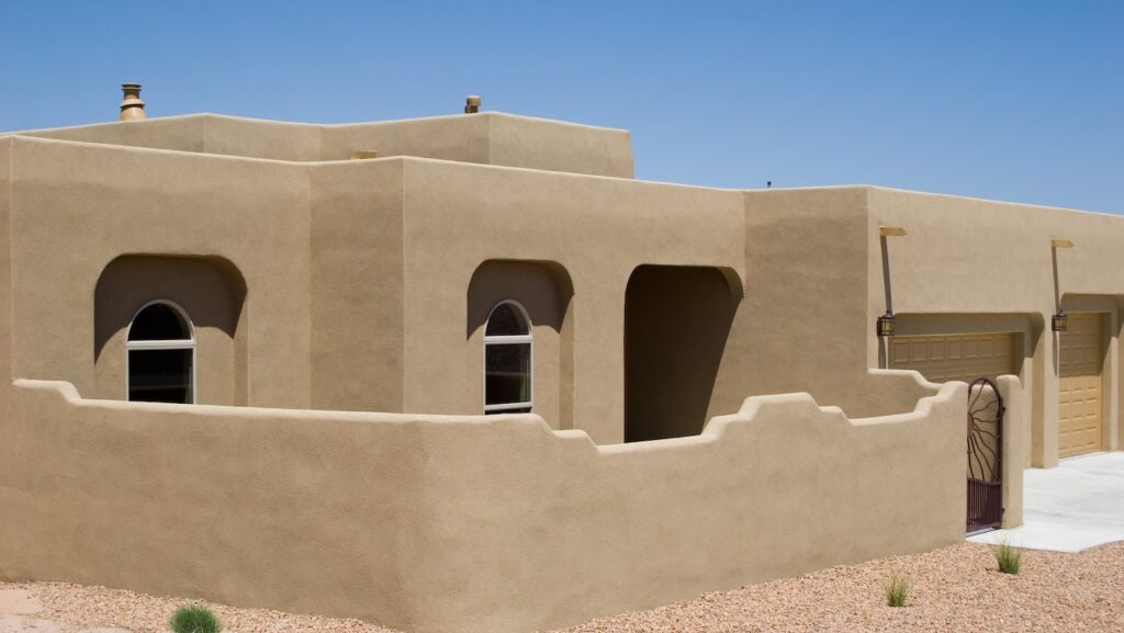 adobe home with stucco exterior and privacy wall