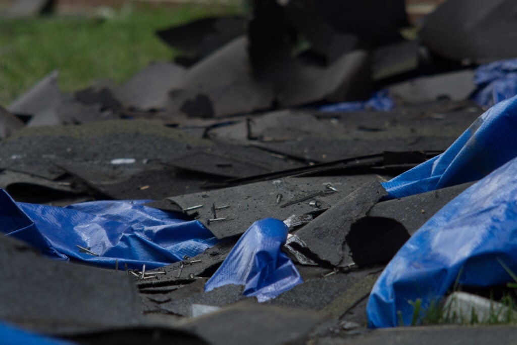 A closeup shot of roof shingles on a blue tarp